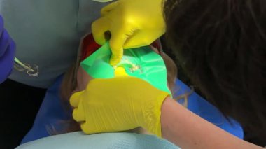 Diş hekimliğindeki kauçuk bant ağzına girmez. Dişçideki kadın. Diş hekimliği mikroskobundaki en son pahalı ekipman..