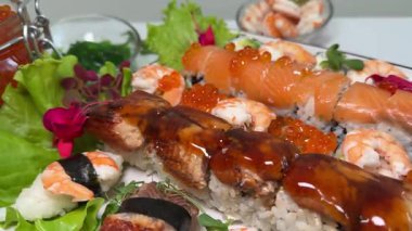 A close-up shot of a sushi platter featuring a variety of rolls with salmon, shrimp, spicy toppings, and decorative garnishes. The platter showcases. High quality 4k footage