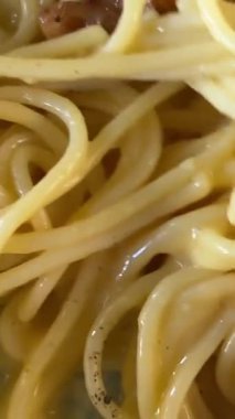 mesmerizing moment captured as a fork gracefully spins through a plate of creamy carbonara. The twirl accentuates the rich textures, creating a visual that invites. stir spaghetti carbonara