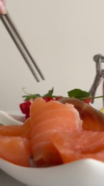 The chefs hand decorates a dish with ham, lemon and sandwiches with red caviar with microgreens. Preparation of dishes for the banquet of a large company. Close-up. High quality 4k footage