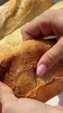 Young girl breaking a french loaf close-up. High quality 4k footage