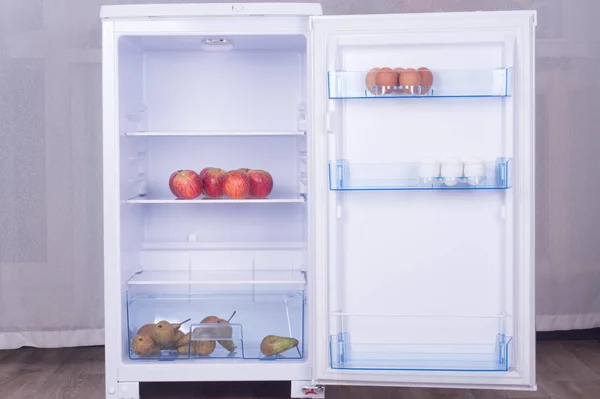 Open fridge, eggs, pears and apples on the shelf of refrigerator, healthy nutrition concept