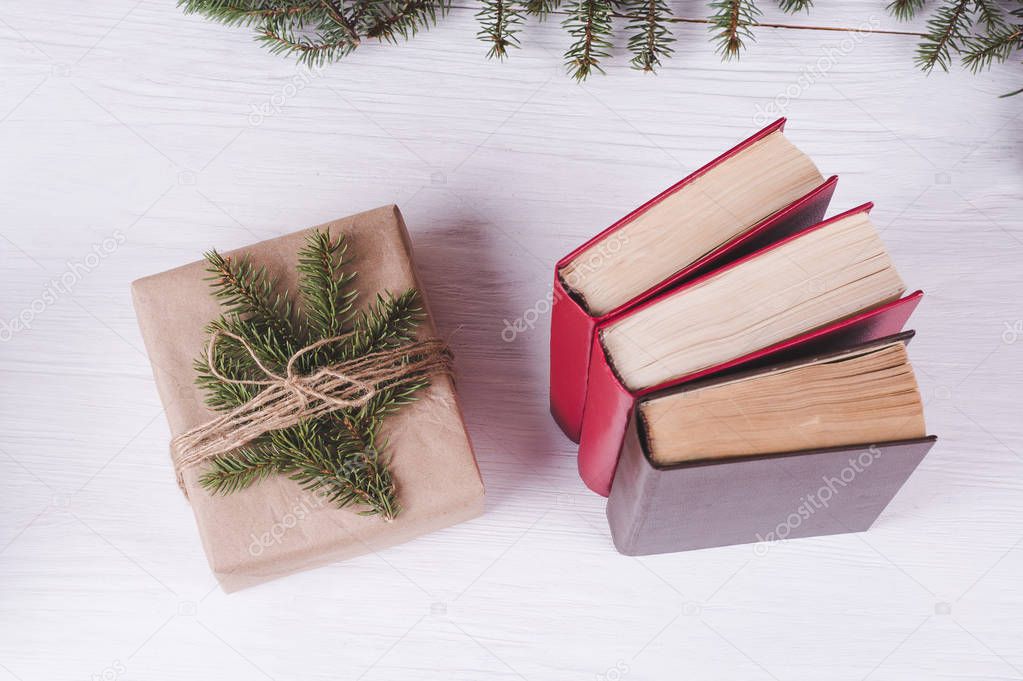 Christmas gift box and old books on a white wooden background. C