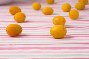 Renkli çizgili masa örtüsü üzerinde sarı erikler. Vejetaryen ya da iyileştirici