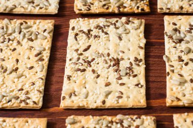 Kırmızı ahşap zemin üzerinde susam, keten ve ayçiçeği olan bir sıra çıtır buğday keki. Vejetaryen yemekleri, ekolojik gıda kavramları.