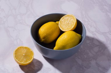 Dilimlenmiş ve bütün limonlar beyaz bir masada ve mavi bir kasede. C vitamini konsepti. Beyaz arkaplan