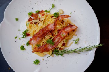 Üstten görünüm beyaz plaka baharatlı domuz pastırması spagetti.