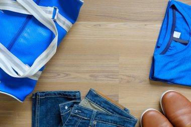Üstten görünüm aksesuarları yolculuğun. Gömlek jeans Ayakkabı ve çanta kopya alanı ile ahşap arka plan üzerinde.