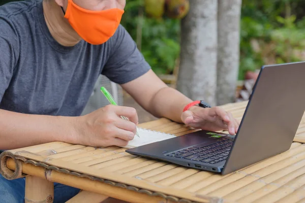 Man is wearing mask and learn online from computer.