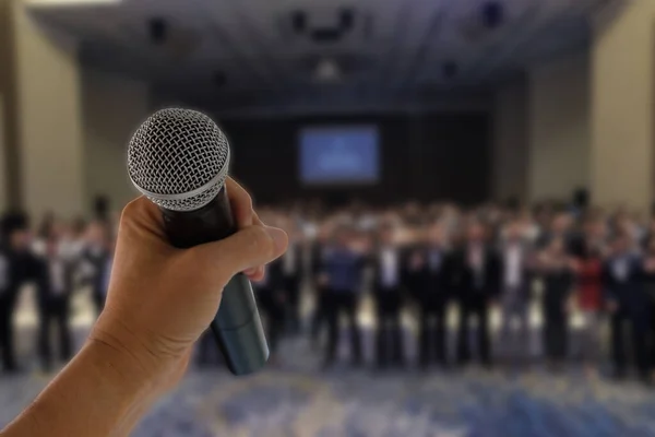 Seminerdeki birçok insanın önünde konuşmaya hazır bir mikrofon var. 
