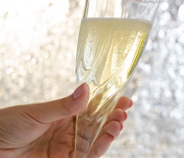 Festeggiamo Natale e Capodanno. La mano femminile tiene e brinda bicchieri di champagne. mano che tiene un bicchiere di vino. Modello fotografico per inviti, saluti — Foto Stock