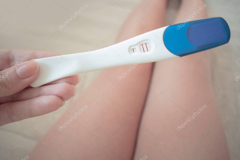 Schwangerschaftstest in weiblicher Hand auf verschwommenem Hintergrund. 