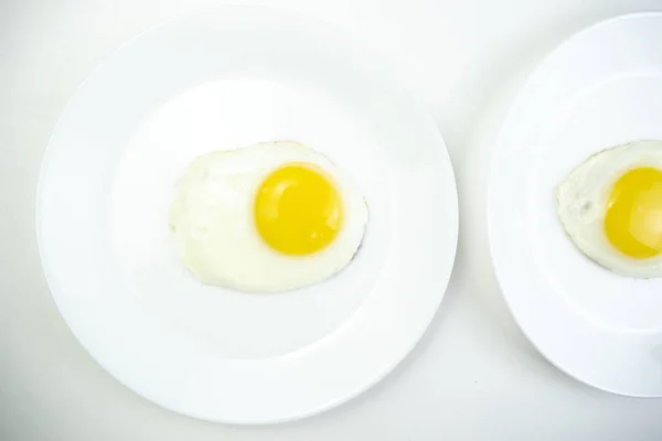 两个煎蛋的传统早餐。白色的盘子，在白色的木制桌子的背景上有鸡蛋。早餐、健康饮食的概念形象. — 图库照片