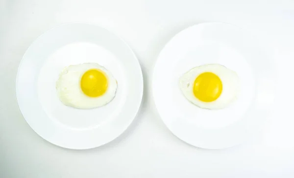 Desayuno tradicional de dos huevos fritos. Placa blanca con huevos en el fondo de una mesa de madera blanca. Imagen conceptual del desayuno, alimentación saludable. — Foto de Stock