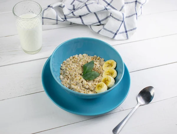 白い木の背景においしいオートミールとバナナスライスとプレート。朝食のコンセプトイメージ、健康的な食事. — ストック写真