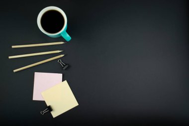 Minimalist iş yeri konsepti, akıllı telefon, kalem ve iş kayıtlarıyla karanlık bir geçmişe sahip. Görüntü dijital, pazarlama, tasarım ajansı. Üst Manzara. Düzleştirme biçimi.