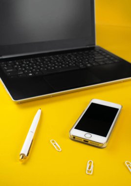 Minimalist iş yeri konsepti, akıllı telefon, kalem ve iş kayıtları ile sarı arka planda. Görüntü dijital ajansı, online eğitim. Resmi kapat