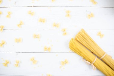 Beyaz ahşap bir masada bir demet uzun, kuru spagetti. İtalyan mutfağı konsepti, yemek malzemeleri. Düz yatıyordu. Üst görünüm