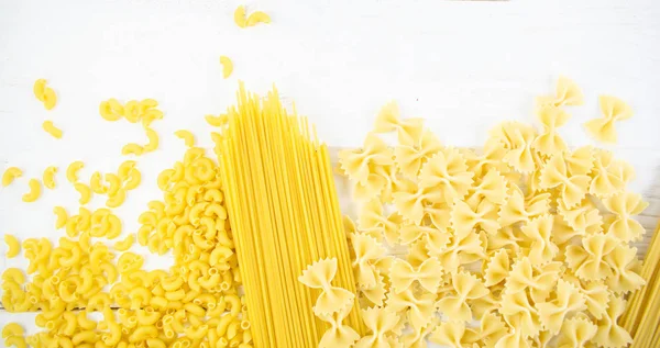 Verschillende soorten pasta op een witte houten tafel. Italiaanse keuken concept, voedselingrediënten. Plat gelegd. Bovenaanzicht, kopieer ruimte — Stockfoto