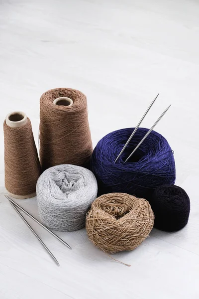 Multicolored threads, skeins and tangles of Italian wool yarn, knitting needles on a white isolated background. The concept of knitting, needlework, handmade.
