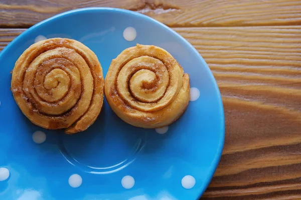 Funny smiley face. Homemade cinnamon rolls on a blue plate stand on a wooden table. Copy space for text. Close up.