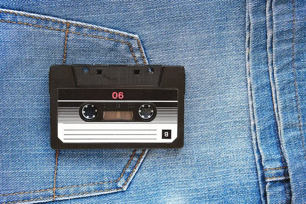 Vintage retro audio cassette on the background of blue jeans, close-up. Media technologies of the past 80-ies. Conceptual picture to illustrate the memories of the past. The view from the top.