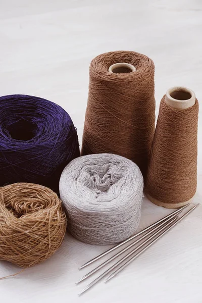 Multicolored threads, skeins and tangles of Italian wool yarn, knitting needles on a white isolated background. The concept of knitting, needlework, handmade.
