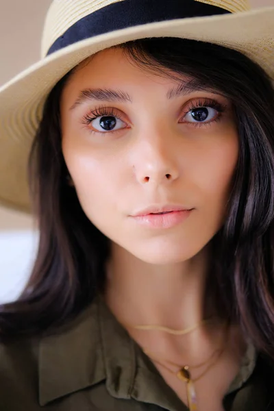 Portrait of a photogenic portfolio of a young model of a girl in a straw hat looking at the camera with a calm look. The concept of fashion and style, cosmetology, natural female beauty.