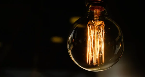 Glass retro light bulb Edison on a dark background. Designer light and lighting in the interiors.