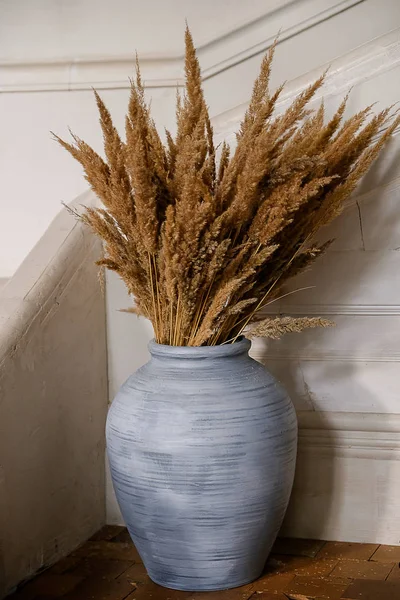 Large blue vase with dried flowers in the interior.