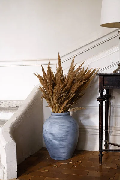 Large blue vase with dried flowers in the interior.