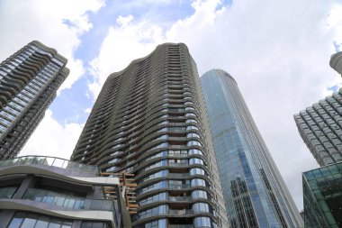 Çok pencereli uzun bir bina bir şehrin ortasındadır. Arka planda başka binalar var.