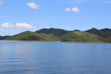Arka planda dağ sırası olan bir su kütlesi. Su mavi, dağlar yeşil.