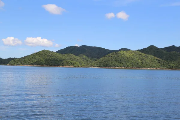 Arka planda dağ sırası olan bir su kütlesi. Su mavi, dağlar yeşil.