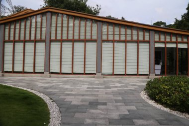 Sergi salonunun dışı tamamen gri fayanslardan oluşmuş, üzerinde ahşap çerçeveler ve önünde kahverengi cam pencereler var. Duvarlarda beyaz ahşap tahıl panelleri var. Bu paneller onlara sıcaklık katıyor.