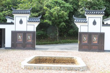 Beyaz duvarları ve siyah kiremitleri olan Çin tarzı bahçe kapısı, iki kapının ortasında açık kare bir ateş çukuruna sahiptir. Girişin etrafı çakıllı yollar ve arkasındaki yeşil ağaçlarla çevrili..