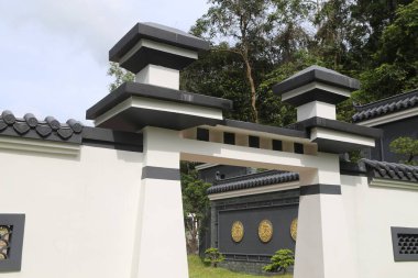 Çin mimarisi tarzında beyaz ve siyah bir kapı. Çatısının üst yüzeyinde basit, koyu gri fayanslar var. Giriş, altın folyo ve yuvarlak tasarımlarla süslenmiş iki kare sütun tarafından çerçeveleniyor. Arkasında büyük bir bahçe görülebilir..