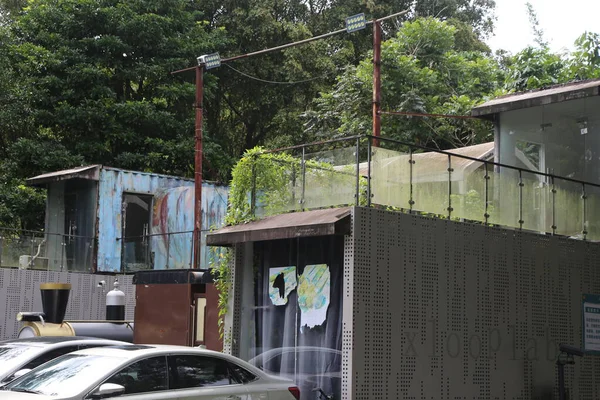 Singapur 'daki terk edilmiş, eski bir binanın dış duvarı ve çatısını biraz grafiti ile görmek. Olay yerinde yan yana iki büyük konteynır var. Aralarında büyüyen bir yeşillik var..