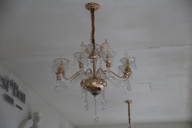chandelier hanging from the ceiling, crystal and brass chandeliers, white walls with gold decoration, vintage style, vintage store, small glass lamp on the wall, chandelier in the corner of the room