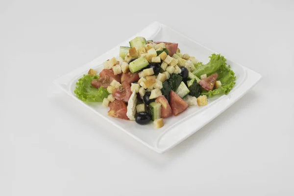 Siyah zeytin, domates, beyaz peynir, salatalık ve beyaz arka plan üzerinde izole soğan taze Yunan salatası plaka. Yakın çekim