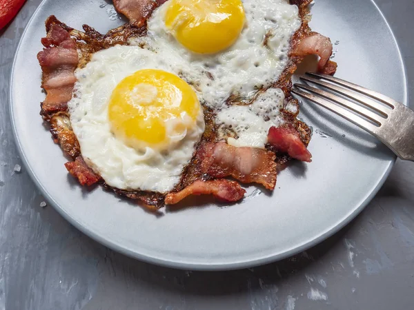 fried eggs from two eggs with fried bacon and red pepper, cupronickel plug