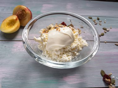 süzme peynir, ekşi krema, nektarin tohumları, mavimsi-pembe tonlarda ahşap bir masa üzerinde kurutulmuş cranberries ile hafif bir kahvaltı