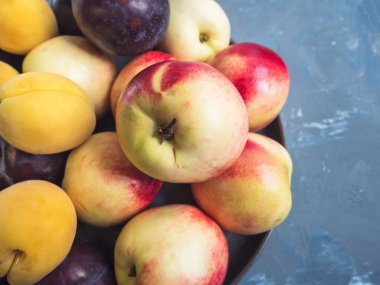 Olgun nektarin ve yuvarlak bir gri Seramik plaka, üstten görünüm üzerinde kırmızı erik. Gri arka plan beton için