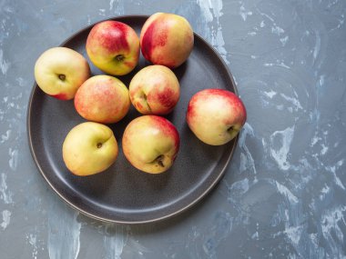 Olgun nektarin yuvarlak bir gri seramik tabak, üstten görünüm. Gri arka plan beton için