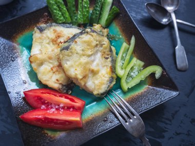 Usefa yararlı kahvaltı kızarmış morina ve karanlık bir arka plan üzerinde taze sebze, taze sebze ve kızarmış morina cutleryul kahvaltı