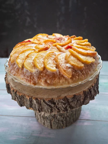 Sweet holiday cake with peaches and cream on a wooden background