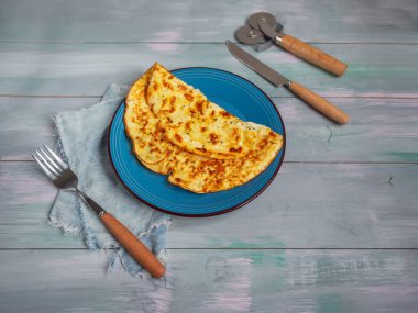 Hafif bir kahvaltı ile mavi seramik plaka üzerinde süzme peynir omlet ve mavi bir arka plan ile bir ahşap tahta.