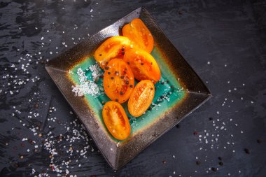 Dilimlenmiş yarıya erik domates baharat, çatal bıçak takımı, mermer yemekler ile tabak