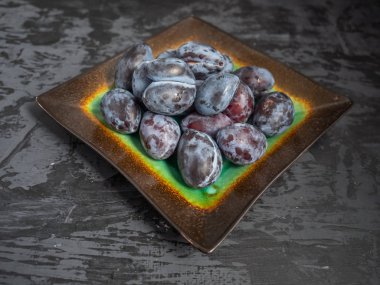 İçinde karanlık bir ahşap arka plan bir seramik dekoratif tabak yakın çekim Olgun Kuru Erik