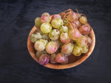 Koyu ahşap arka plan üzerinde bir bambu Kupası closeup Olgun üzüm. Yakın çekim.